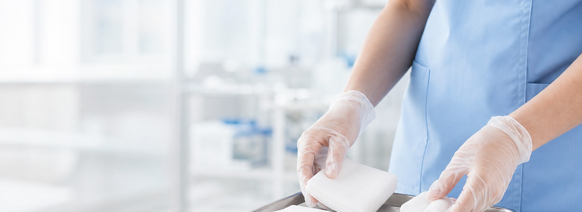Nurse arranging gauze and cotton rolls on a sterile tray